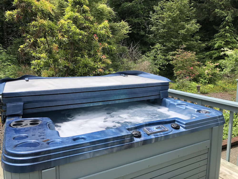 A blue hot tub with the lid open.