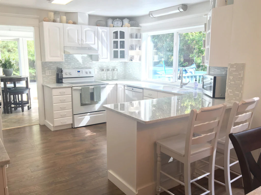 A kitchen with white cabinets and wooden floors.