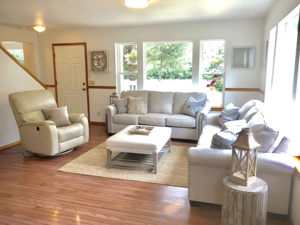 A living room with white furniture and wood floors.