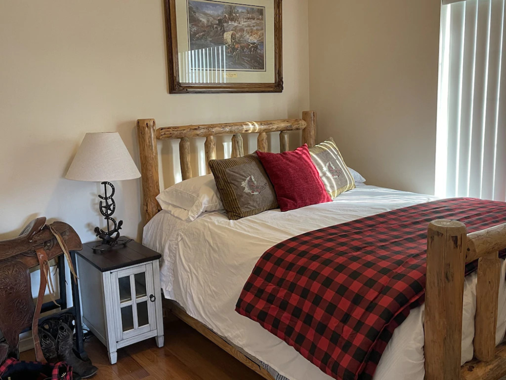 A bedroom with a bed, nightstand and lamp.