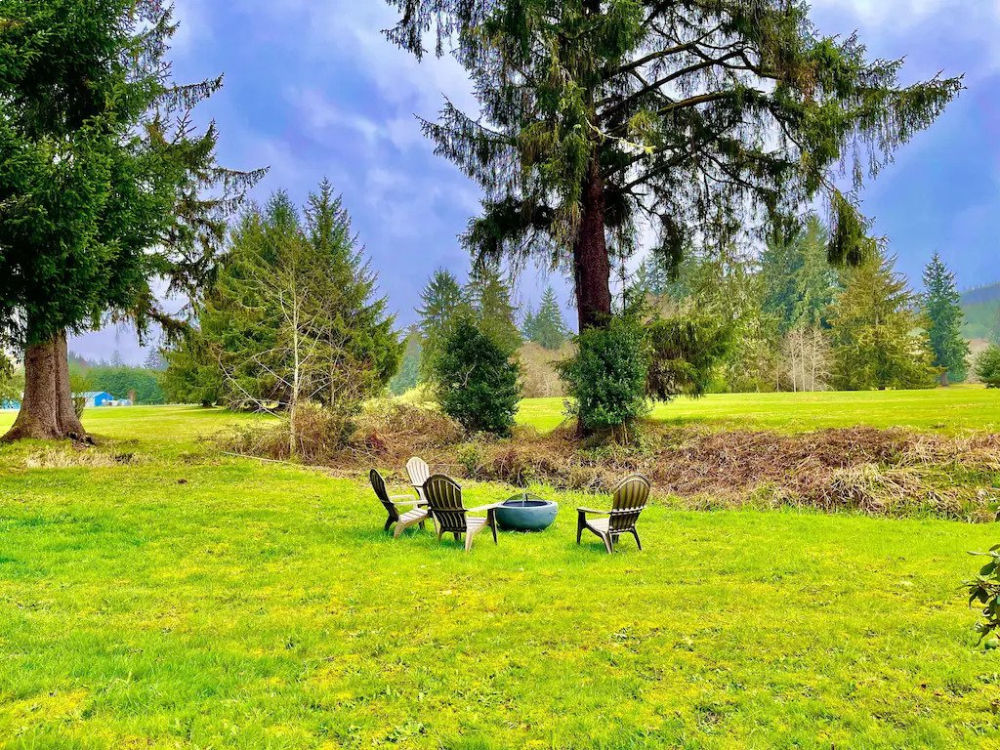 A group of people sitting in the grass near trees.