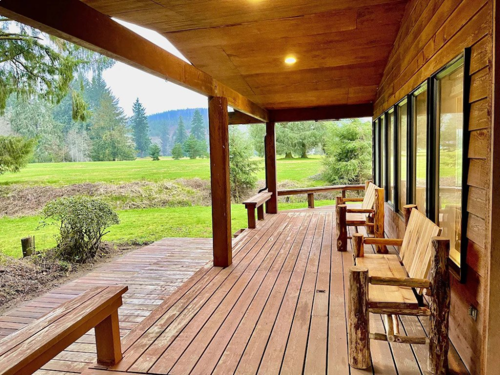 A porch with wooden benches and grass in the background.