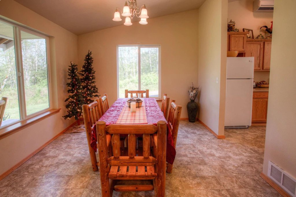 A dining room table with chairs and a refrigerator.