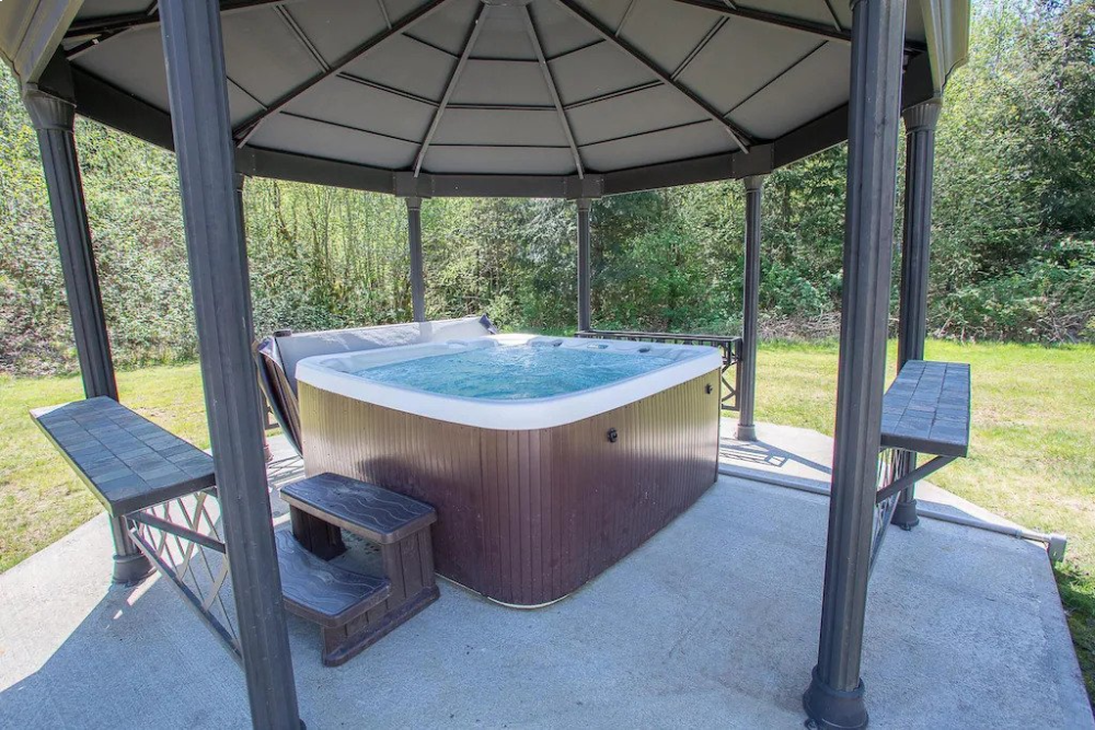 A hot tub in the middle of an outdoor gazebo.