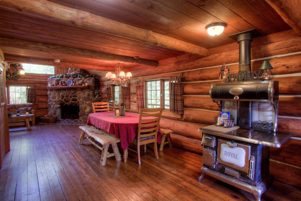 A log cabin with wood floors and a fireplace.