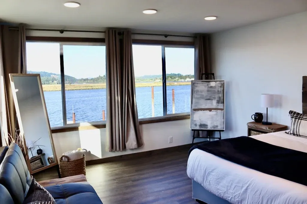 A bedroom with a large window overlooking the water.